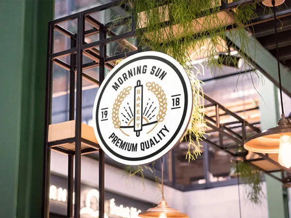 Circular Shop Sign Attached to Building Decorated with Plants and Lamps Mockup 1