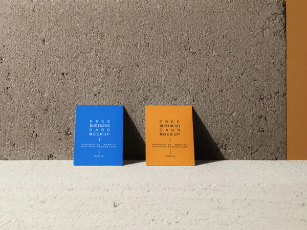 Front View of Two Vertical Business Cards Against Concrete Wall Mockup 1