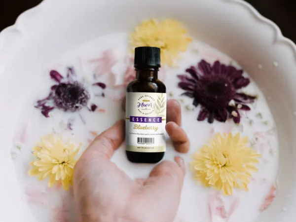 Hand Holding Food Essence Bottle with Milk and Flower Around Mockup 1