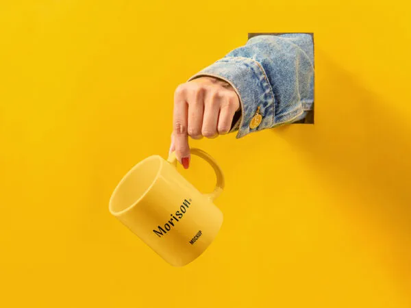 Hand Holding Mug out of Hole on the Wall Mockup 1