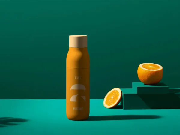Juice Bottle Mockup in a Solid Color Background Next to Sliced Orange 1