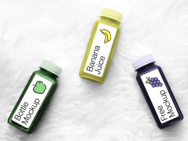 Mockup Featuring Three Bottles of Juice Laying on a Fluffy Background 1