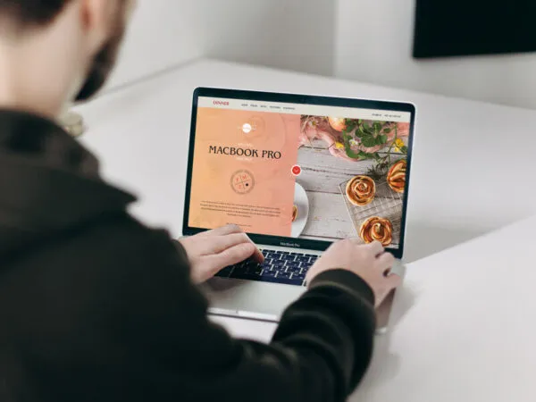 Mockup Featuring a Man Using MacBook Pro on a Table 1