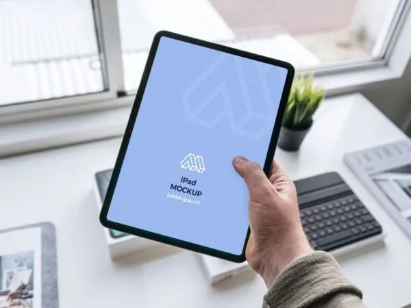 Mockup Showcasing Hand Holding iPad in a Office Table Scene 1