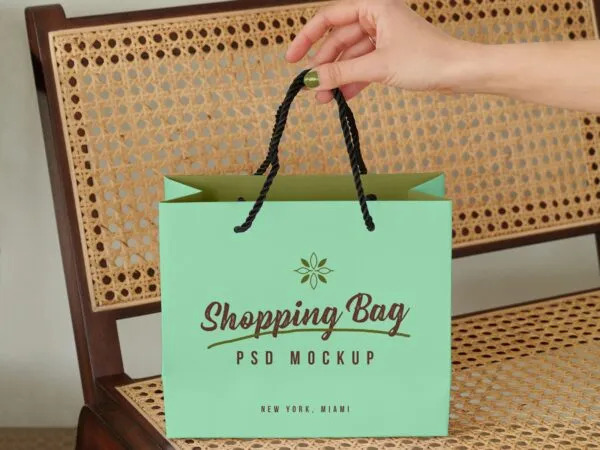 Mockup Showing a Hand Holding Shopping Bag on a Bench 1