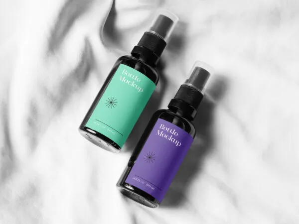 Two Small Spray Bottle on a Soft Sheet Mockup 1